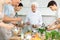 Elderly chef imparting cooking skills to group at culinary courses