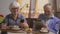 Elderly couple drink tea in their dining room sitting at a table with gadgets