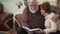 Elderly couple look into a big book or album, having a pleasant conversation, nostalgic and laughing