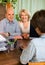 Elderly couple of pensioners talking with employee