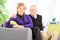 Elderly couple posing seated on a sofa at home