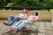 The elderly couple relax in lounges on sunny terrace