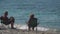 An elderly couple is sitting in beach chairs by the sea on a pebble beach and relaxing. Slow motion close-up. The