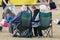 An elderly couple sitting in fold up camping chairs at an outdoor event
