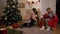 Elderly couple sitting near fireplace decorated for Christmas. Cozy home. The husband lights the fireplace, the wife