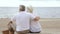 Elderly couple sitting together on beach and looking to sea.