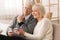 Elderly couple with smartphones, watching photos at home