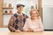 Elderly couple standing in a kitchen behind a wooden table