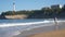 An elderly couple stands on the beach and looks at the ocean