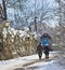 Elderly couple take a walk on a snow path with small chapel in w