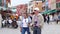 Elderly couple of tourists with cameras walking along the street with colorful houses in weekends