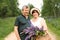 An elderly couple walks through the forest and a man gives a woman a woven basket with a bouquet of flowers of purple lupines