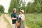 An elderly couple walks through the forest and a man gives a woman a woven basket with a bouquet of flowers of purple lupines