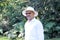 Elderly dark-skinned Latino man in his 60s relaxed in his retirement dressed in a guayabera, hat and sunglasses walks in the park
