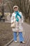 An elderly , elegantly dressed woman walks along an alley in a public Park