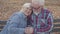 Elderly European couple sitting on the bench and talking. Mature husband calming down his beautiful senior wife. Aging