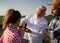 Elderly expert collecting soil sample talking with two young farmers