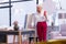 Elderly fancy businesswoman standing in the office holding a phone