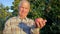 Elderly Farmer Agronomist Holding A Ripe Apple In The Garden In Light Of Sunset