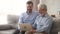 Elderly father and son sitting on couch laughing watching video