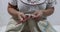 Elderly female hands removing the stitch marker and starting to weave the border in beige cotton thread