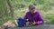 Elderly female hiker resting on bench reading smartphone outdoors in nature