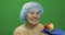 Elderly female lady in protective hat. Doctor shows her an apple