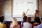 Elderly female lecturing students together with her male assistant, showing, explaining