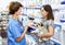 Elderly female veterinarian recommending pet food to young woman visiting pet store with her puppy