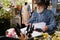 Elderly florist working in flower shop with smartphone