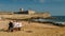 Elderly friends sit on a beach overlooking the 16th Century Saint Julian Fortress at Carcavelos beach near Lisbon