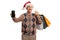 Elderly gentleman with a christmas santa hat showing a mobile phone and holding shopping bags