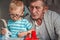 Elderly grandfather plays with little grandson with plastic blocks