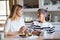 An elderly grandmother with an adult granddaughter sitting at the table at home, eating cakes.