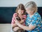 Elderly grandmother and granddaughter stroking a purebred Siamese cat at home