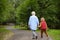 Elderly grandmother and her little grandchild walking together in sunny summer park. Grandma and grandson. Two generations of