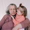 An elderly grandmother holds a beautiful little girl in her wrinkled arms. family generation. Youth and old age