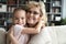 Elderly grandmother hugs little cute granddaughter smile looking at camera