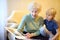Elderly grandmother and little grandchild looking family photos album. Grandma and grandson