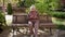 An elderly grandmother is sitting on a bench with a phone in her hands.