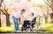 Elderly grandmother in wheelchair with granddaughter in spring nature.