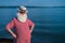 Elderly gray-haired man with a beard in a striped bathing suit and hat posing on the beach. Senior citizen on vacation