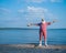 Elderly gray-haired man with a beard in a striped bathing suit and hat posing on the beach. Senior citizen on vacation