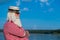 Elderly gray-haired man with a beard in a striped bathing suit and hat posing on the beach. Senior citizen on vacation