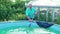 An elderly gray-haired man cleans the walls of the pool with a mop.