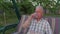 The elderly and gray-haired man sitting on the garden swing and drinking water.