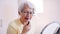 Elderly gray haired woman applying eyebrow pen in the office