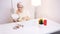 Elderly gray haired woman applying make up in the office