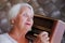 Elderly grey-haired woman listening vintage radio