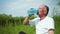 Elderly handsome man enjoys life and drinks pure healthy water from sports bottle after playing sports